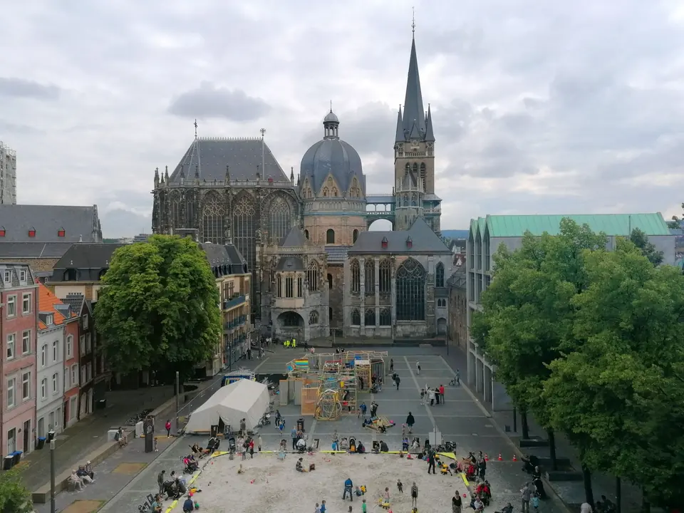 Luftaufnahme des Aachener Doms mit umliegender Architektur und Spielplatz.