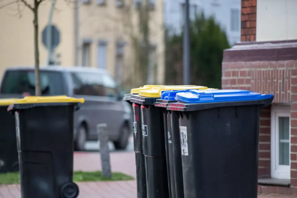 Farbcodierte Mülltonnen in einer Stadtstraße in Gütersloh, Deutschland, die das städtische Abfallmanagement zeigen.