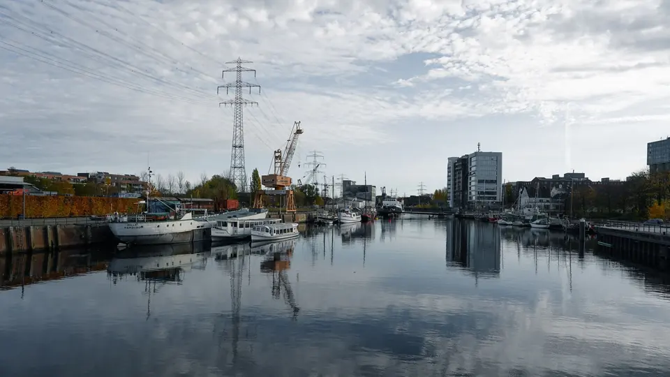 Idyllische Szene mit Booten im Hamburger Hafen, spiegelndem Wasser und Stadtkulisse.