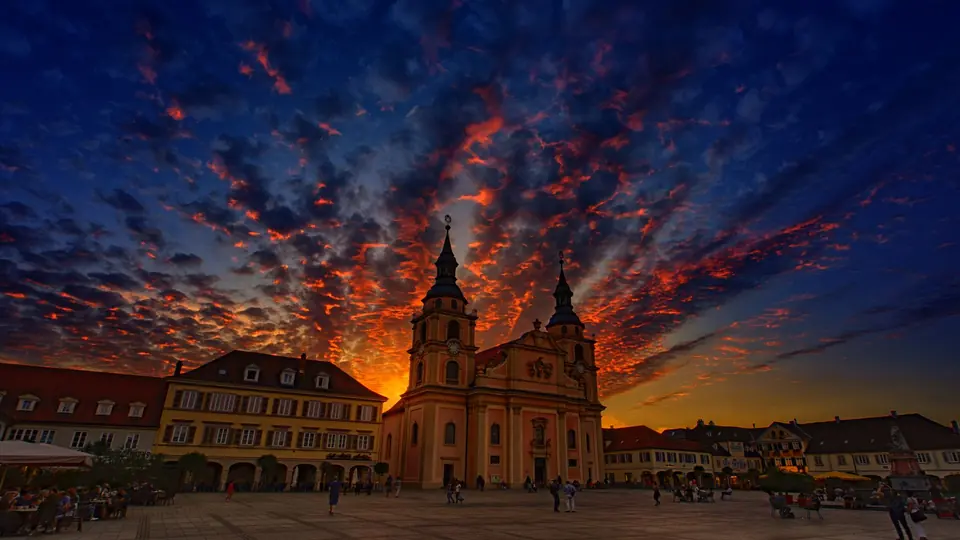 Eindrucksvolle Sonnenuntergangsansicht einer Kirche in Ludwigsburg, Deutschland, mit lebhaften Wolkenformationen.